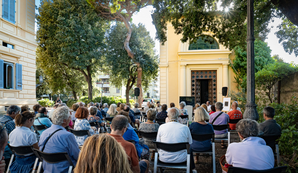 gruppo di persone sedute in un parco che assistono ad una conferenza