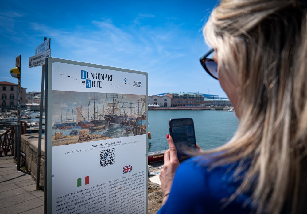 Persona che scansione il qr code di uno dei cartelli di lungomare ad arte in prossimità del porto mediceo